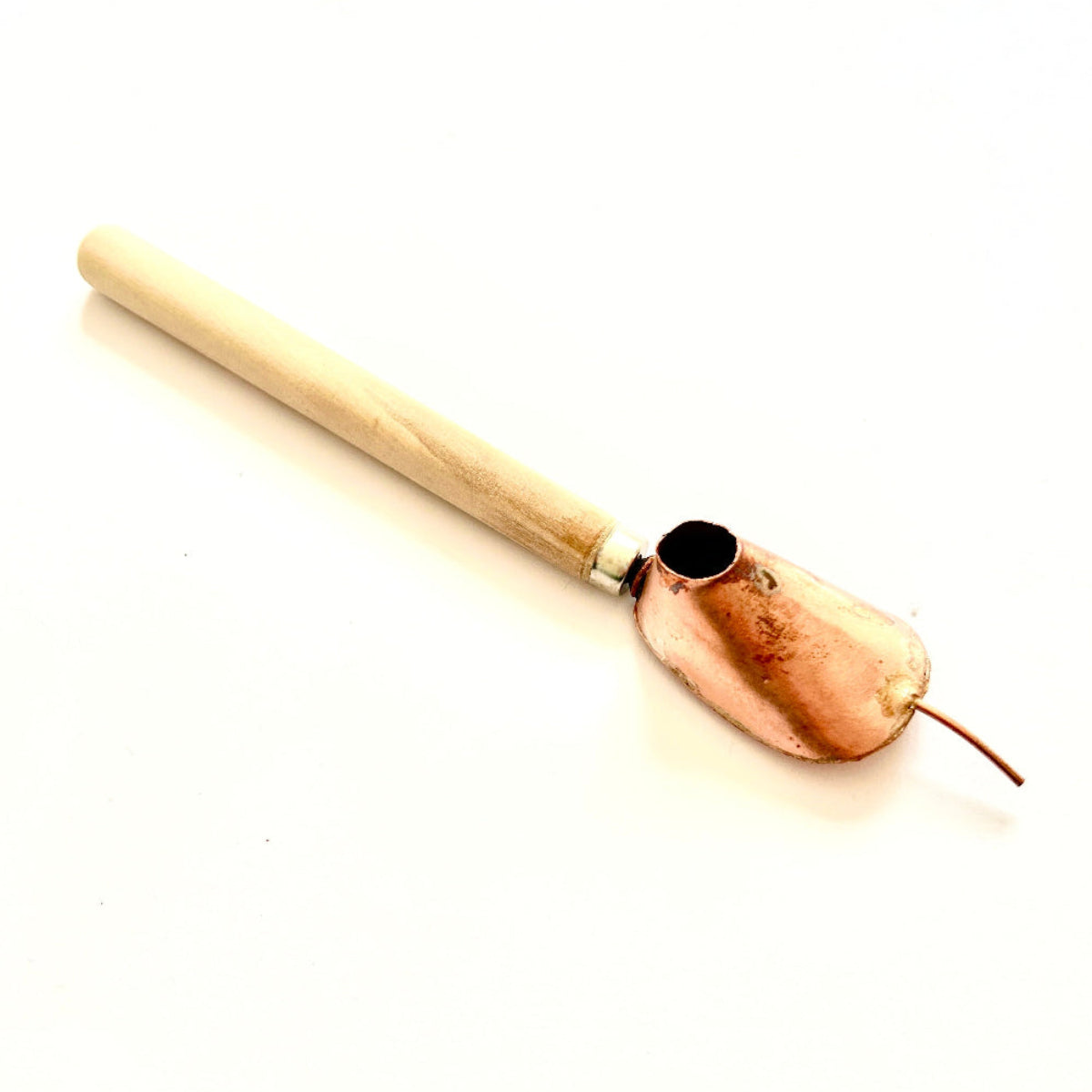 A traditional batik tjanting tool with a wooden handle and copper wax reservoir, featuring a fine spout for applying hot wax onto fabric.
