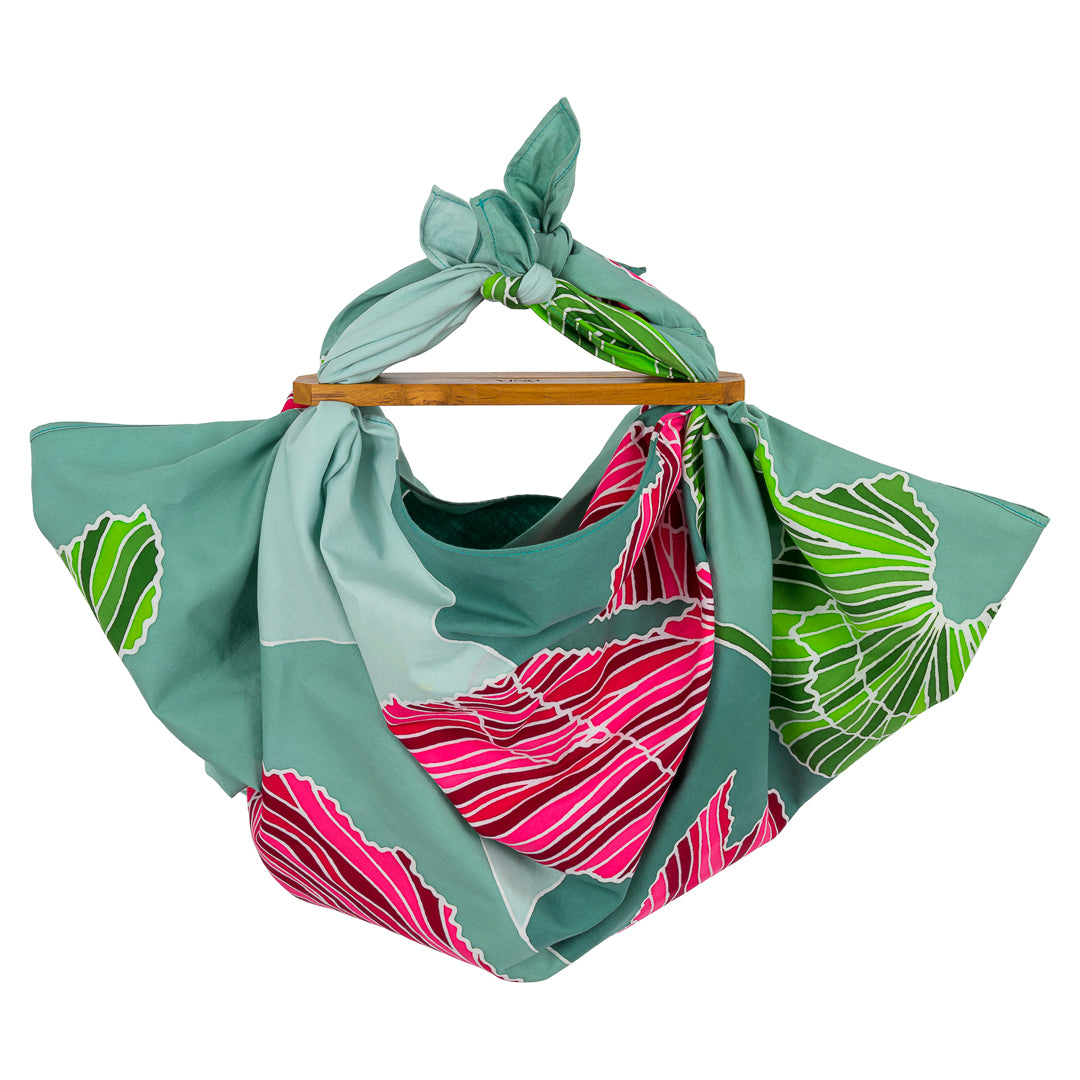 Batik Ying batik satin cotton scarf with green and pink leaf patterns folded on wooden handle