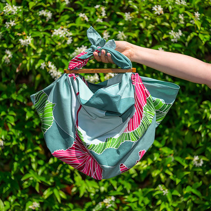 Hand holding colourful batik satin cotton scarf with green and pink floral patterns by Batik Ying