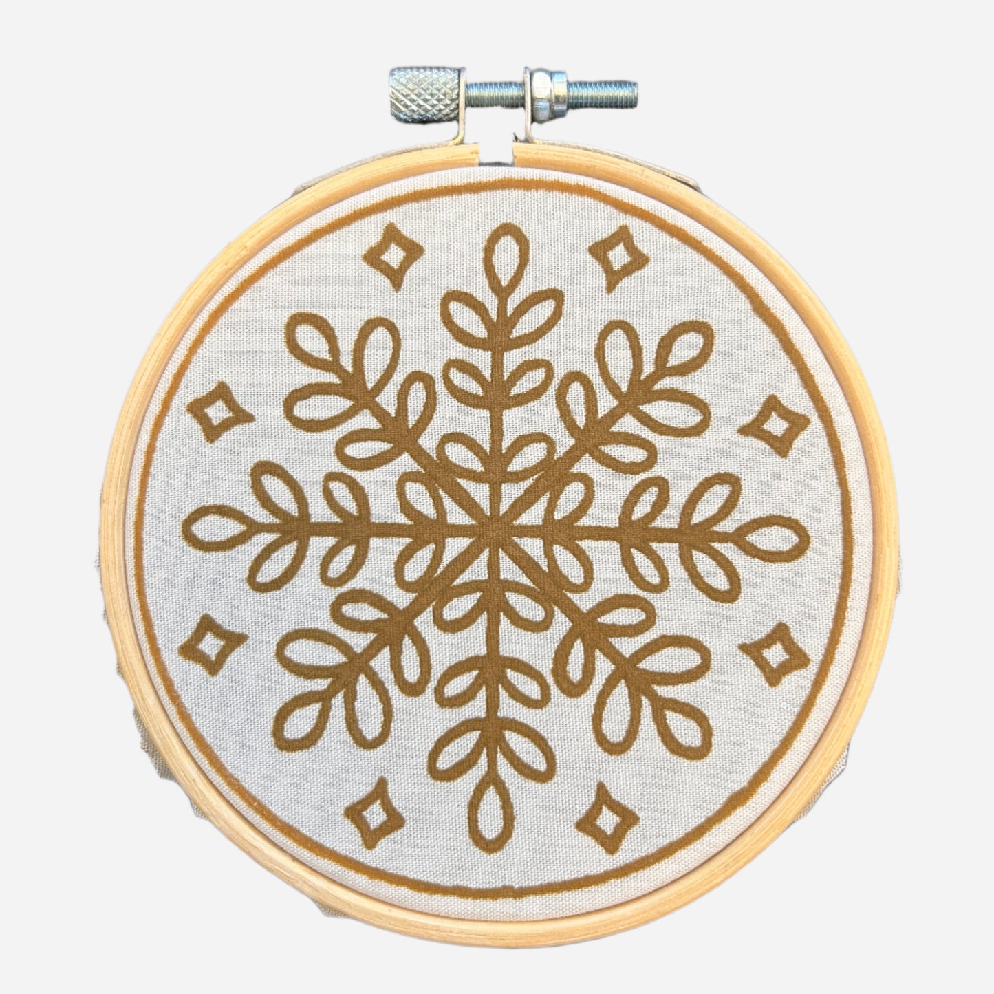 Batik Ying DIY kit featuring a mini batik snowflake ornament with brown geometric design on fabric in wooden hoop