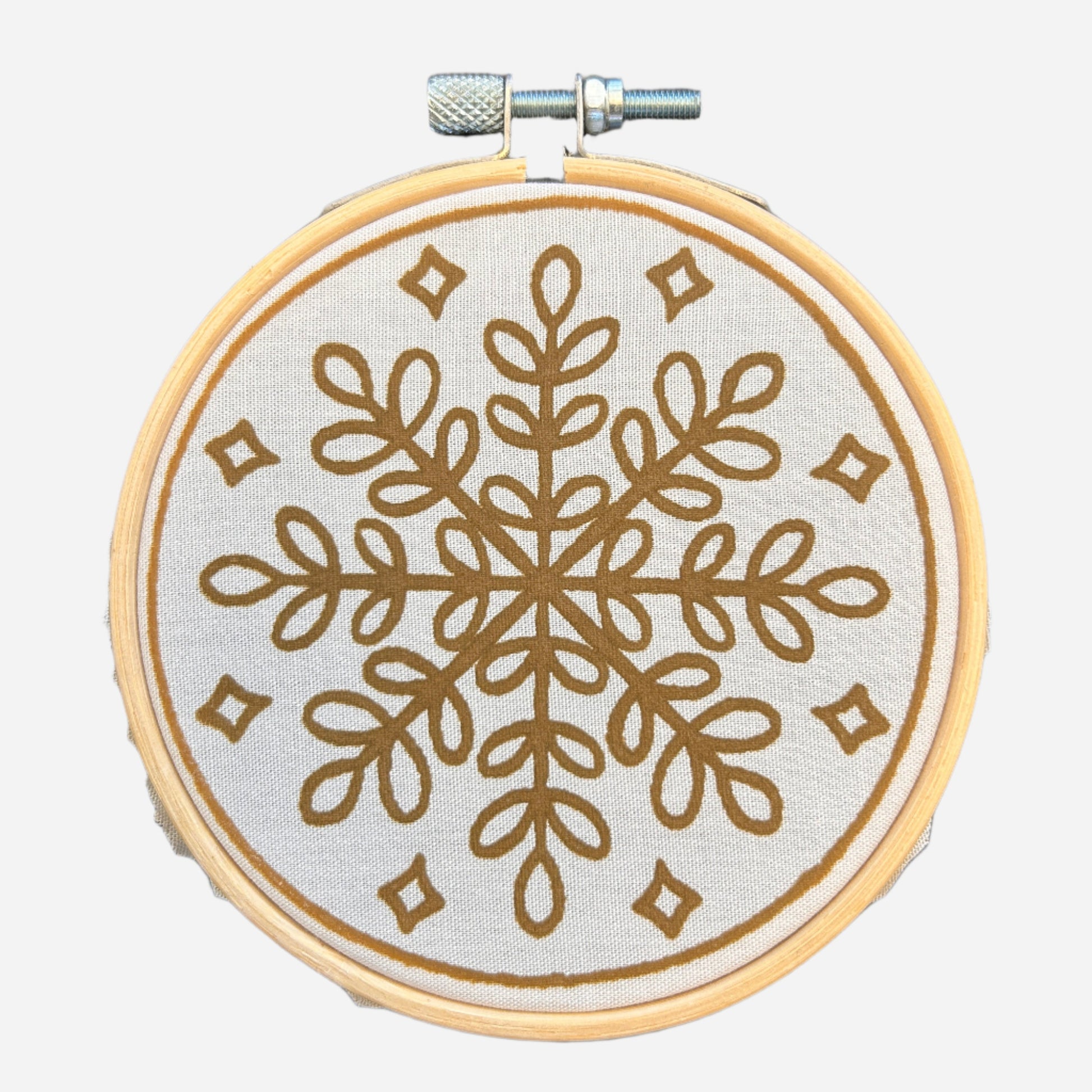 Batik Ying DIY kit featuring a mini batik snowflake ornament with brown geometric design on fabric in wooden hoop