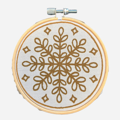 Batik Ying DIY kit featuring a mini batik snowflake ornament with brown geometric design on fabric in wooden hoop